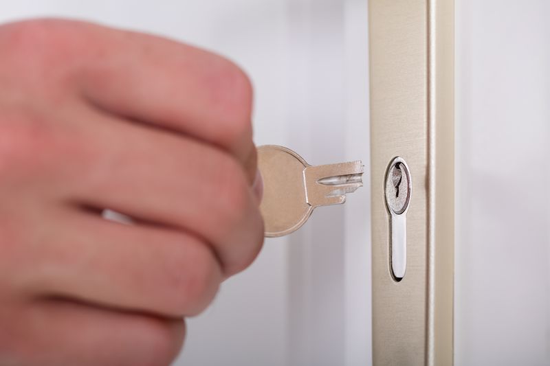 Close-up Of Person's Hand Holding Broken Key Inserting In Keyhole